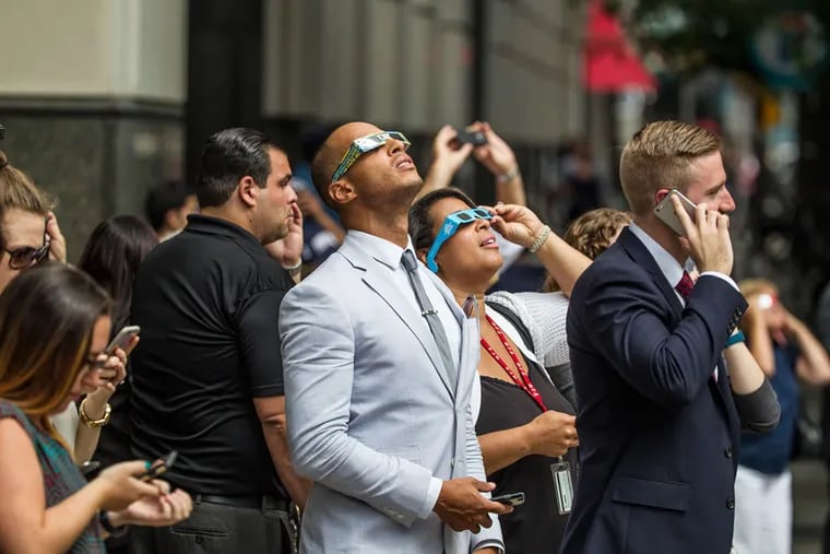 Viewers stop in front of Philadelphia City Hall in August 2017 to gaze at at the last solar eclipse. Today's eclipse will begin across the Delaware Valley a little after 2 p.m.