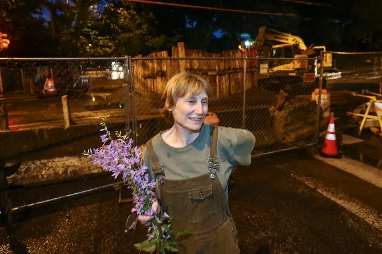 A Facebook event welcomed people to make offerings to a big sinkhole at 43rd and Baltimore, as if the sinkhole were a deity. Here is Ann Dixon with her offering.