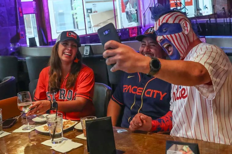 Jamie Pagliei, also known as “Philly Sport Guy” takes a selfie with Maria Montalvan, left, and Roger Montalvan, at Sambuca, a restaurant and bar in Houston, while Phillies fans tailgate there prior to Game 1 of the World Series.