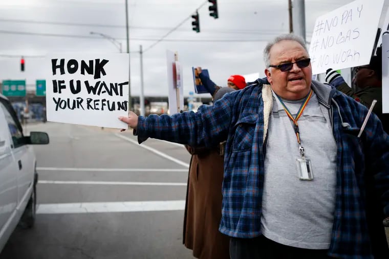 In this Jan. 10, 2019, photo, Will Kohler, an IRS tax examiner, holds a protest sign as union members and other federal employees rally to call for an end to the partial government shutdown outside the IRS site, in Covington, Ky. (AP Photo/John Minchillo)