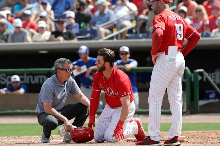 Phillies Bryce Harper yells towards Blue Jays pitcher Trent Thornton with Manager Gabe Kapler and assister trainer.Chris Mudd during the sixth-inning in a spring training game on Friday, March 15, 2019 at Spectrum Field in Clearwater, FL.