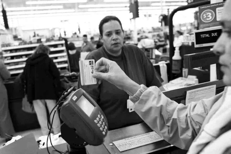 Luz Rodriguez (right) uses a debit card to pay for her items at a Wal-Mart Supercenter in Denver.