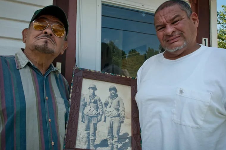 Emerito Bermudez, left, whose infantry unit was awarded the Congressional Gold Medal this year, poses with a photo of himself and a friend during the Korean war. His son, Orlando Bermudez, is on the right. ( RON TARVER / Staff Photographer )