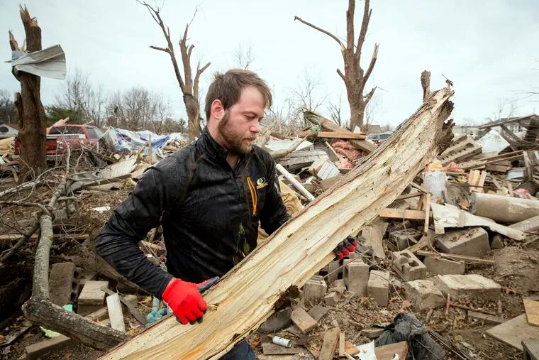 Steven Tirpak cleans debris from the remains of his two-story home in Taylorville, Ill., Sunday, Dec. 2, 2018. Tirpak and his infant were not home when the storm struck. The National Weather Service says multiple tornadoes touched down in central Illinois, damaging dozens of structures and injuring multiple people. (Ted Schurter/The State Journal-Register via AP)