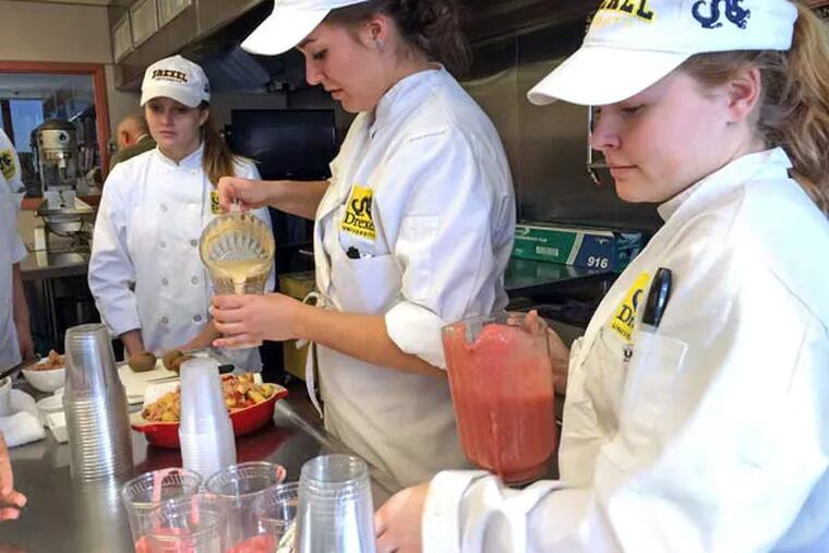 Drexel Food Lab students Emily Crasnick, Ally Zeitz, and Alexandra de los Reyes pour smoothies made from overripe bananas and strawberries. (SANDY BAUERS / Staff)