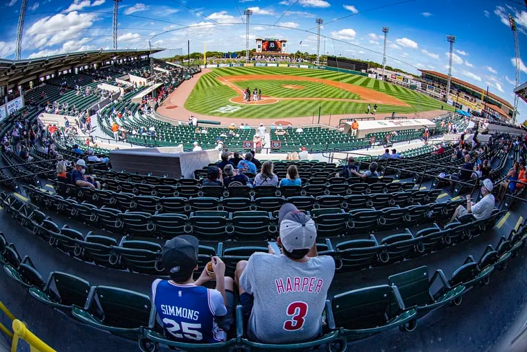 Fans watch from the outfield lawn Sunday, as the Phillies opened their exhibition season against the Detroit Tigers at Joker Marchant Stadium in Lakeland, Fla.