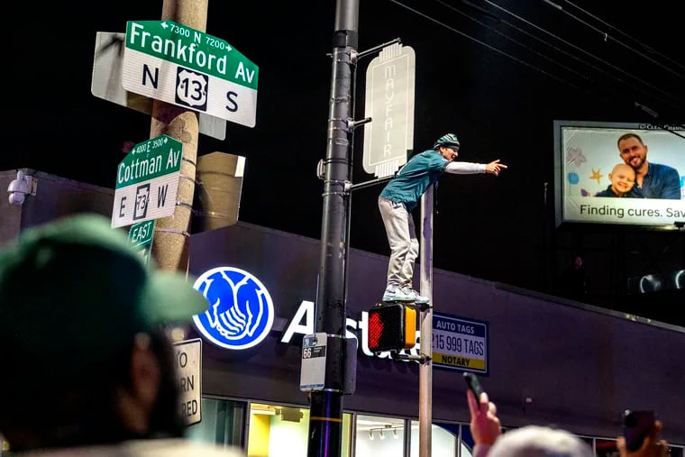 A fan climbs a pole at Cottman and Frankford Avenues in Mayfair following the Eagles’victory over the San Francisco 49ers in the NFC Championship.