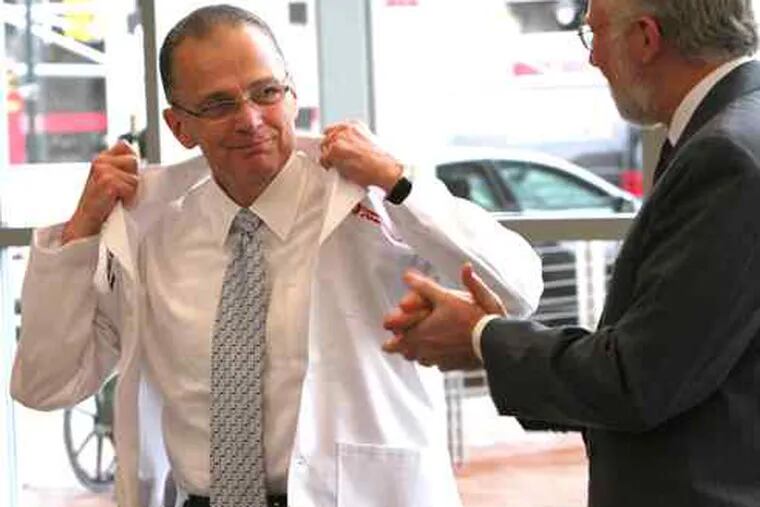 Paul Katz accepts a lab coat from Rowan University president Donald Farish. Katz, who was introduced at a news conference Wednesday, will serve as dean of Rowan's new medical school.