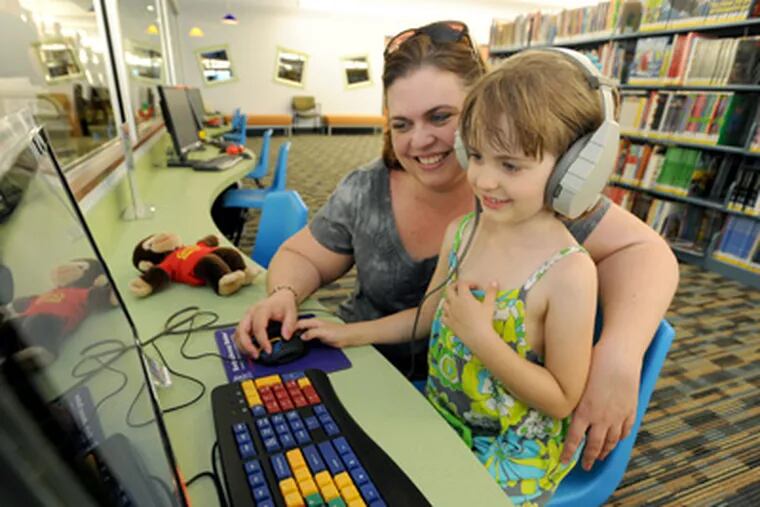 At the relocated, upgraded Margaret E. Heggan Free Library in Washington Township, Jillian Schultz, 5, tries out a computer with her mother, Stacy. (April Saul / Staff Photographer)