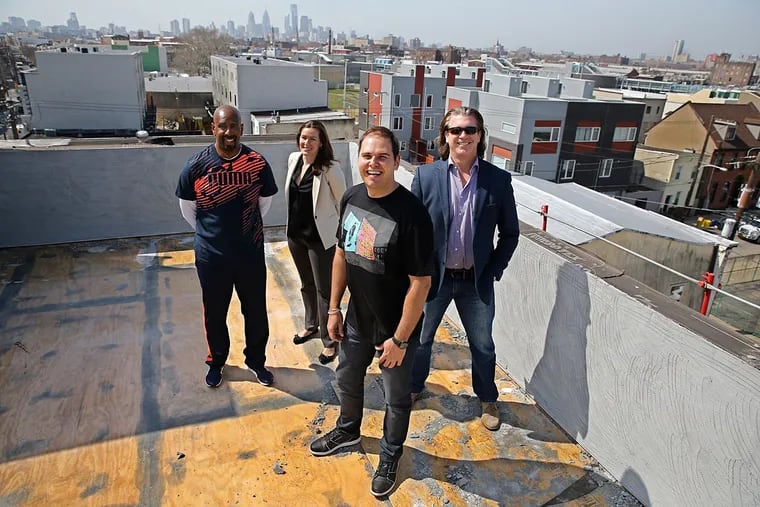 Jeff Tubbs (front) is joined atop a new condo building on the 2000 block of Frankford Avenue by fellow Urban Roots members Jahmall Crandell (left), Claire Laver, and Jim Maransky.