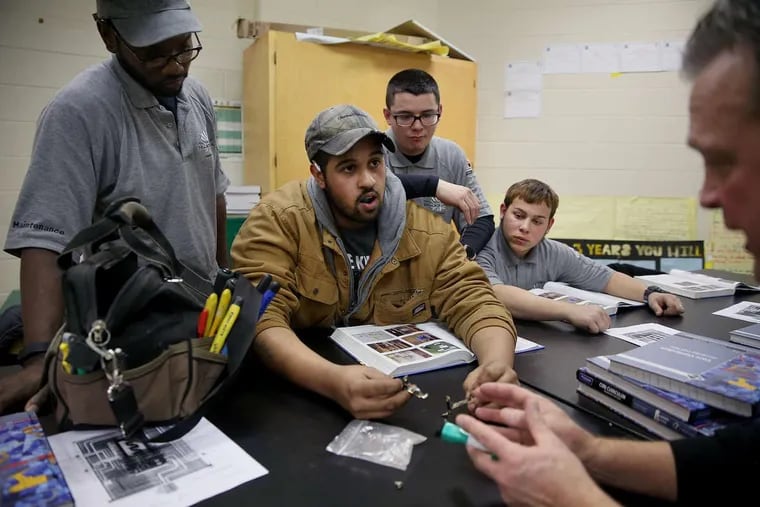 Apprentice electrician Derek Beaudry, second from left, shows off a piece of a heating element that disintegrated during his workday to his fellow apprentices. He’s part of a new School District apprenticeship program. Apprenticeships are a large part of the Kenney workforce committee’s strategy.