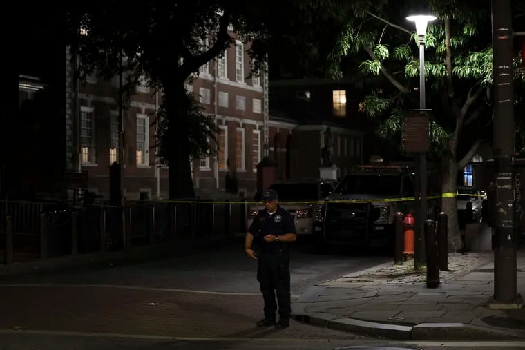 A member of the Philadelphia Police Crime Scene Unit looks over the scene of a fatal shooting near Independence Hall on Saturday night.