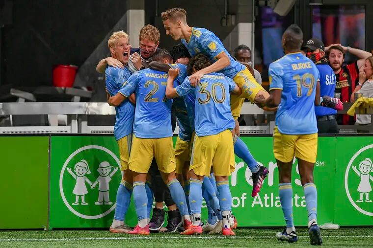 Jakob Glesnes (left) nearly knocked Jim Curtin's glasses off as the Union celebrated Glesnes' goal in the 93rd minute to steal a 2-2 tie at Atlanta United on Sunday.