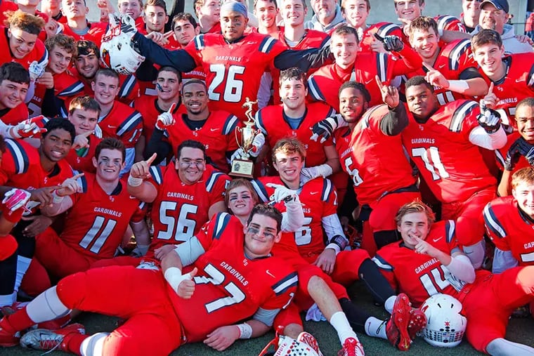 Upper Dublin players pose with their trophy after the Cardinals defeated North Penn, 46-21, Saturday in the District 1 Class AAAA football final at Souderton.
