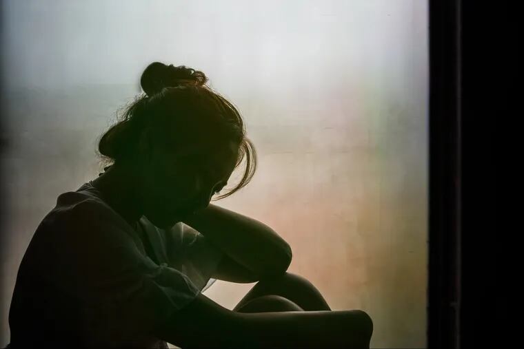 Vintage filtered on silhouette of depressed girl sitting on the window