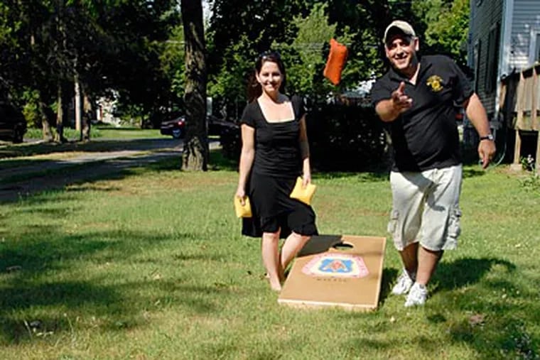 We Are American founders Michele and Ed Secrest with a cornhole board donated to the group by the New Jersey Carpenters Training Center in Hammonton. (RON TARVER / Staff Photographer)