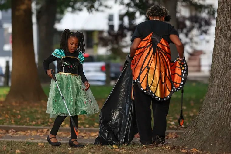Devon Allen, 6, left, and Carmela Dow cleaned up the park during a Spooky Clean-Up event hosted by Climate Action Pa. and Friends of Malcolm X Park at Malcolm X Memorial Park in West Philadelphia on Wednesday.