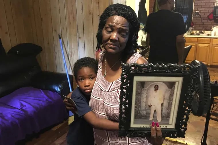Hester Carlyle and great-grandson T.J. with a photo of his father, Tyreas Carlyle. Tyreas, who was shot by police Friday, used a walker to get around, his grandmother said.