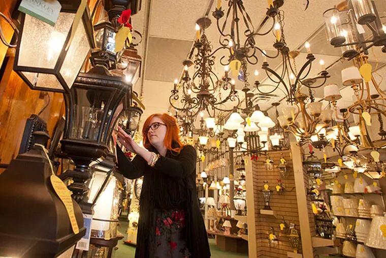 Even though businesses across butler Pike in Ambler have no electricity due to the recent ice storm, Katie Murdoch of Denney Electric Supply is bathed in light as she checks the price on a fixture on Thursday, Feb. 6, 2014. ( RON TARVER / Staff Photographer )