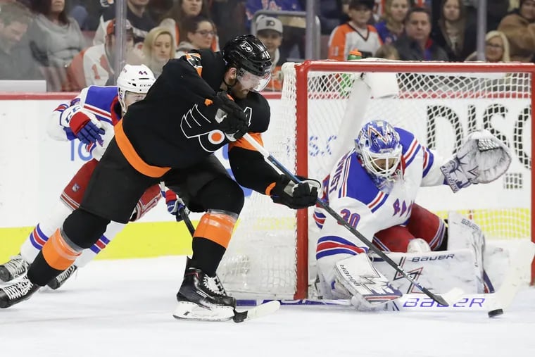 Flyers center Sean Couturier back hands the puck against New York Rangers goaltender Henrik Lundqvist and defenseman Neal Pionk in the first-period on Friday, November 23, 2018 in Philadelphia. YONG KIM / Staff Photographer