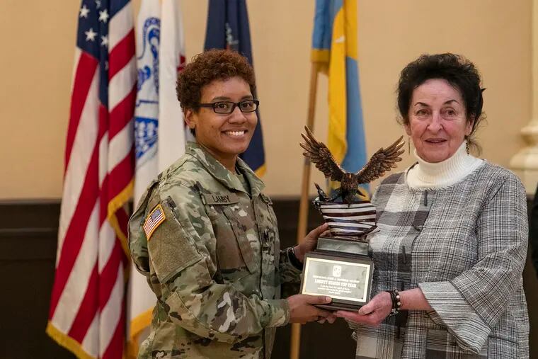 ROTC Dragon Task Force Cadet Battalion Cmdr. Shadira Lamby (left) and Joan McVeigh DeNofa, daughter of Sgt. John McVeigh, with the Liberty Stakes trophy at Drexel Armory on Thursday. Sgt. McVeigh was posthumously awarded the Medal of Honor for heroism displayed during combat in World War II.