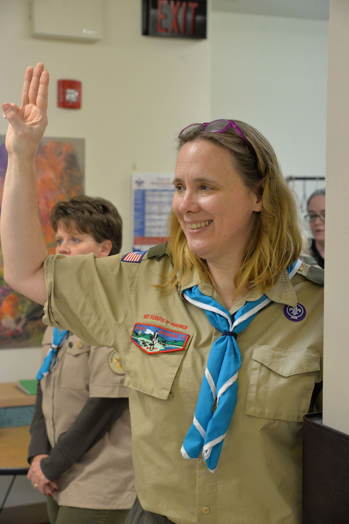 Scoutmaster Melissa Pendill calls the meeting to order with the scout sign, the first three fingers on the right hand raised.