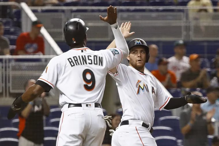 The Marlins' Austin Dean, right, high-fives Lewis Brinson, left, after they scored in the second inning against the Phillies.