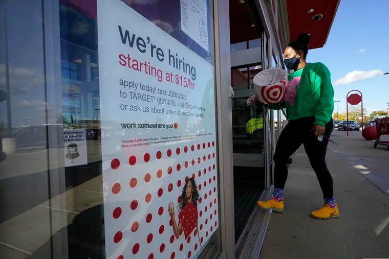 In this Sept. 30, 2020, file photo, a passerby walks past a hiring sign while entering a Target store in Westwood, Mass. The retailer is offering reservations to customers who don't want to brave the crowds.  (AP Photo/Steven Senne, File)