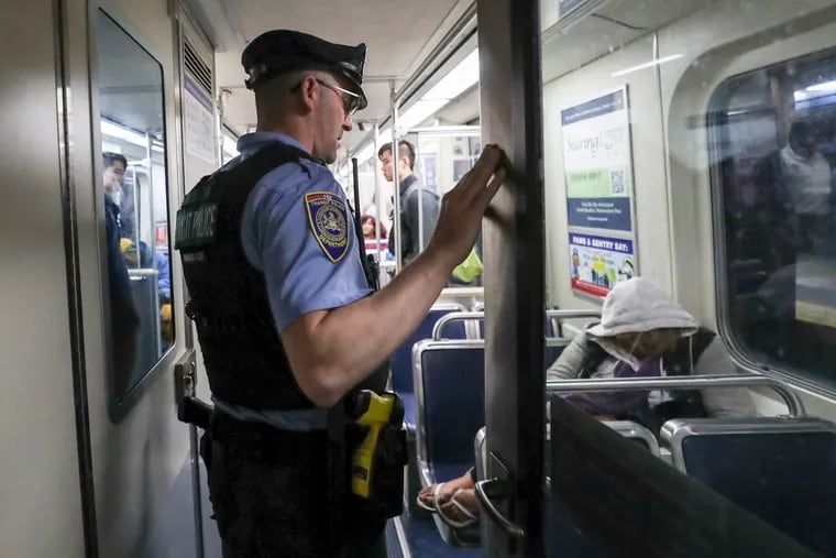 SEPTA police officer Martin Zitter wakes up a passenger in a deep sleep to make sure they are OK on an eastbound El train in Philadelphia in May.