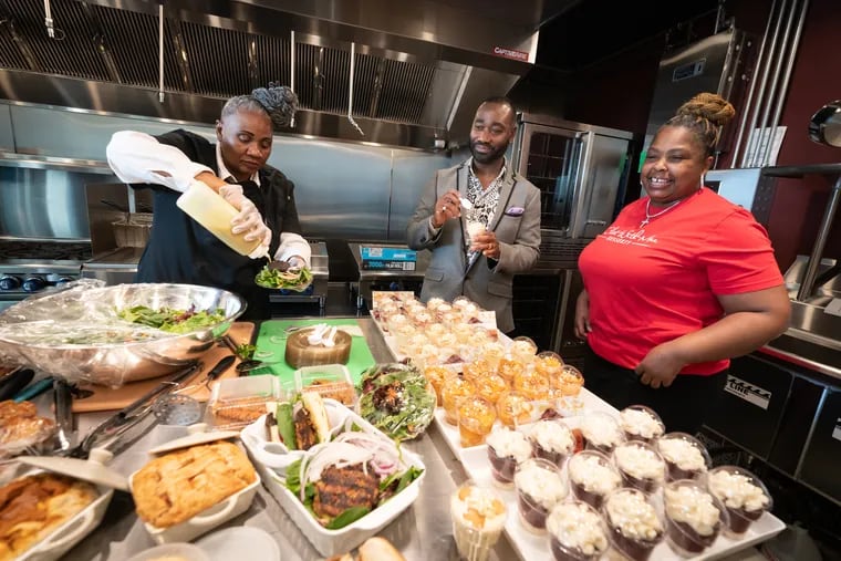 Alonzo Coate, owner of Kitchen Korners, a commercial kitchen in Northeast Philadelphia, with two of the chefs who lease his shared kitchen space: Mary “Ma Dookz” Muse (left), who is preparing salmon cakes, and Helena Geraldine, a baker and caterer who prepared an array of desserts.