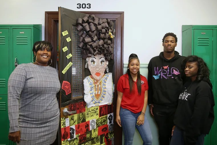 From left, early childhood education teacher Myra Evans and sophomores Tramaine James, 16; Love Coleman, 16; and Russia Cox, 15, stand for a portrait next to Evans' classroom door decorated for Black History Month at Parkway West High School in West Philadelphia on Thursday, Feb. 21, 2019. Evans and the students put together the decoration.
