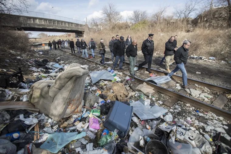 Members of a group that were shown the largest open air drug market in Kensington walk the Conrail tracks amid the piles of garbage that litter the right of way of the rail tracks to see another area that is used as a shooting gallery.