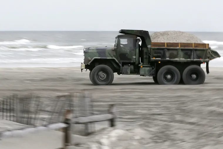 Trucks and earthmoving equipment on the Avalon beach at 33rd Street are part of the sand-shifting effort.