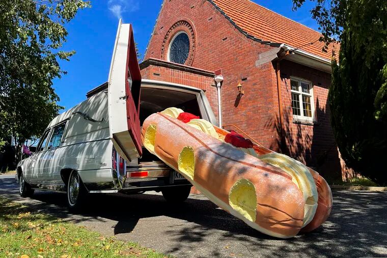 This photo provided by Ross Hall, shows a cream doughnut shaped coffin for the funeral of Phil McLean outside a church in Tauranga, New Zealand on Feb 17, 2021. Auckland company Dying Art makes unique custom caskets which reflect the people who will eventually lay inside them, whether it's a love for fire engines, a cream doughnut or Lego. (Ross Hall via AP)