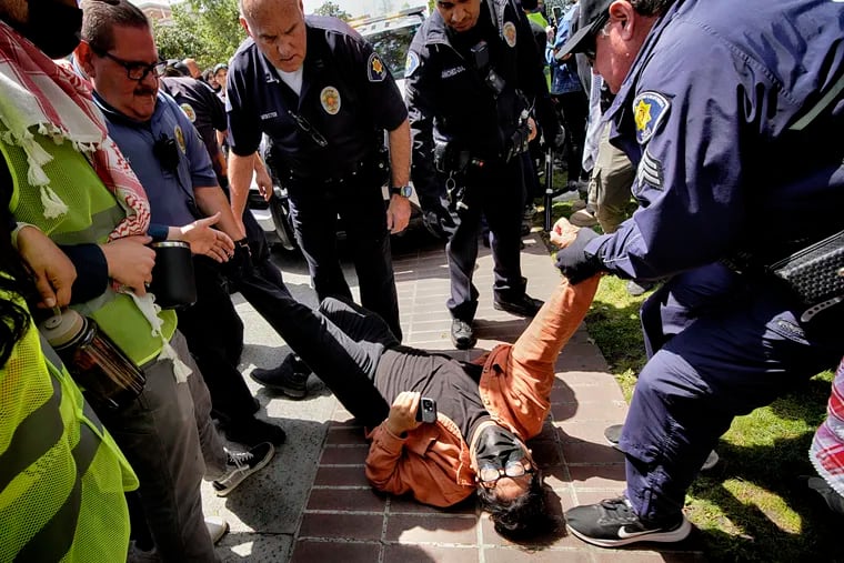 A University of Southern California protester is detained by USC Department of Public Safety officers during a pro-Palestinian occupation at the campus' Alumni Park on Wednesday, April 24, 2024 in Los Angeles.