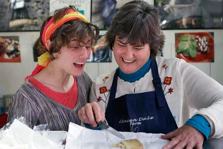 Mary Meillinger (right) and her daughter, Carrie (left) cut samples of Tomme de Linden Dale, a naural hand aged goat cheese, at their Linden Dale Farm stand in the Lancaster Central Market. ( MICHAEL S. WIRTZ / Staff Photographer )