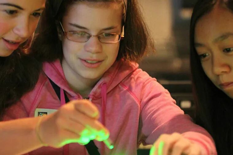 File: In a laser session at West Chester University's Super Science Saturday, students (from left) Sara Parker, Sarah Redmile, and Victoria Le shine red and green beams light on a gummy bear Saturday, November 1, 2014. The program educates girls about the various careers that are available in the STEM fields (science, technology, engineering and math).