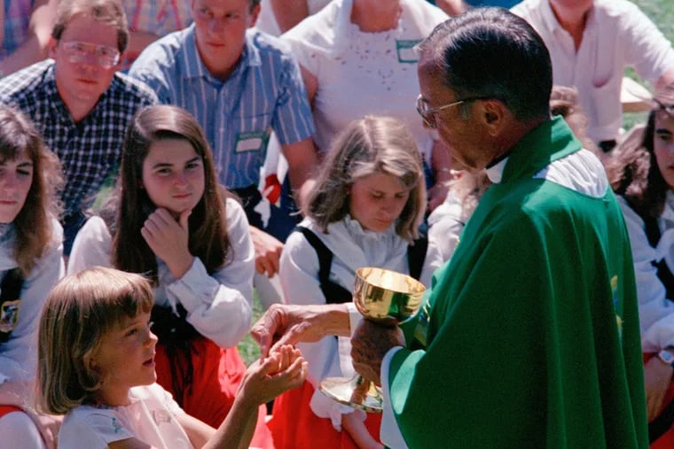 This 1988 photo shows Rev. Joseph Hart dispensing communion during an outdoor Mass.