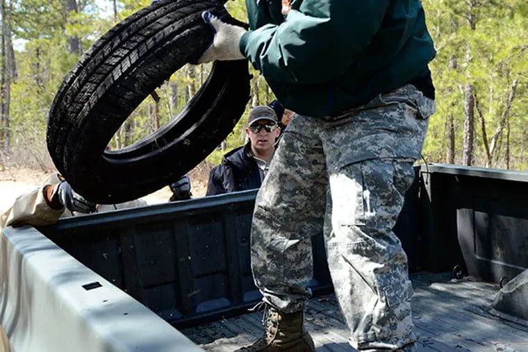Volunteers help cleanup tires dumped in Brendan T. Byrne State Forest in Burlington County, NJ, after the announcement of a crackdown on illegal dumping in state parks, forests, wildlife management areas and natural lands March 27, 2014. ( TOM GRALISH / Staff Photographer )