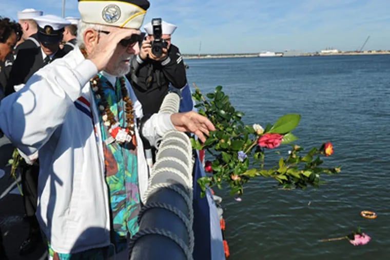 Pearl Harbor survivor Ed Kmiec salutes as he throws flowers over the rail during a remembrance ceremony, in Jacksonville, Fla.
