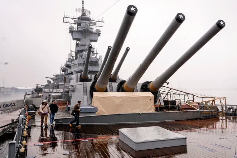Visitors cross under the big gun turrets on the deck of the Battleship New Jersey on Thursday, Dec. 28, 2023. The ship is headed for a homecoming of sorts as it prepares to leave its berth on the Camden Waterfront for a short hop across the Delaware to Philadelphia, where it was launched in 1942.