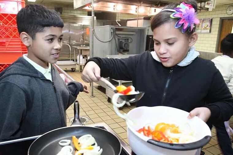 Yariel Fernandez and Lixjohanne Alicea begin saut&#0233;eing onions and peppers for the chicken quesadillas. The classes took place in the Bayard Taylor school kitchen.