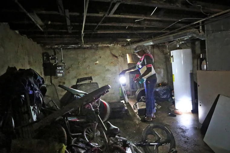 With a lantern, Odessa Washington, 39, looks through her water- damaged basement after the earlier water pipe rupture, Monday June 15, 2015. ( DAVID SWANSON / Staff Photographer )