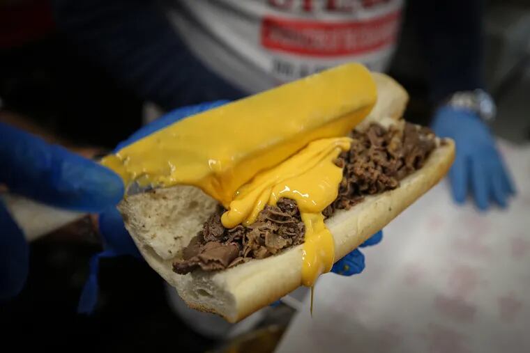 Frank Olivieri Jr., owner of Pat’s King of Steaks, puts cheese on a steak sandwich at his shop at Ninth and Passyunk.