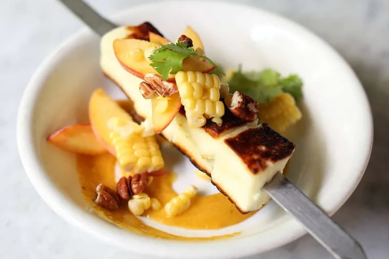 The new, summer version of Zahav's haloumi is grilled over coals with peaches and sweet corn.