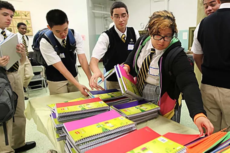 Kianna Cruz (right) picks out notebooks provided by the school. In less than two years, Cristo Rey Philadelphia raised more than $5 million to help get it off the ground. (Michael Bryant/Staff)