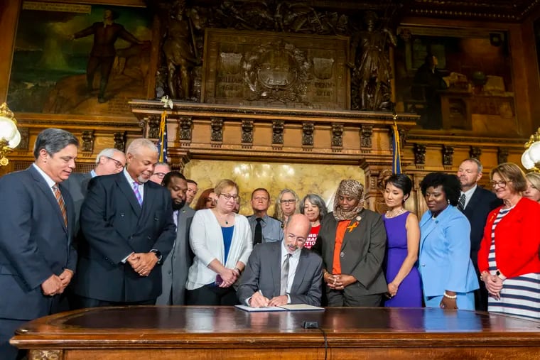 Pa. Gov. Tom Wolf signs executive order to reduce gun violence during a ceremony at the state Capitol on Friday, Aug. 16, 2019 in Harrisburg, Pa.   Watching are, from left, Senate Democratic Leader Jay Costa, Allegheny County, Sen. Tony Williams, D-Philadelphia, Rep. Jordan Harris, D-Philadelphia, Shira Goodman, CeaseFire Pa., Rep. Movita Johnson-Harrell, D-Philadelphia, Patty Kim, D-Dauphin County, Rep. Joanna McClinton, D-Philadelphia and Rep. Maureen Madden, D-Monroe County.