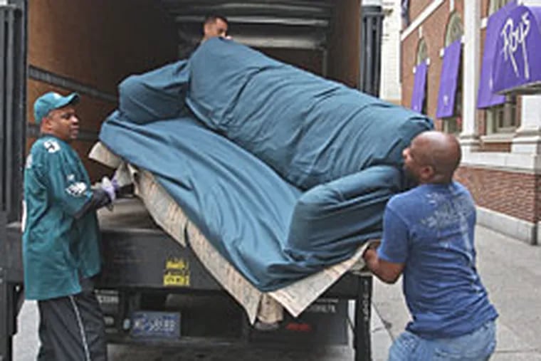 Michael Bowens, right, and Donald Brown, left, struggle to load one of four couches donated by the Obama for President campaign office at 1500 Sansom St. to the Philadelphia school system.