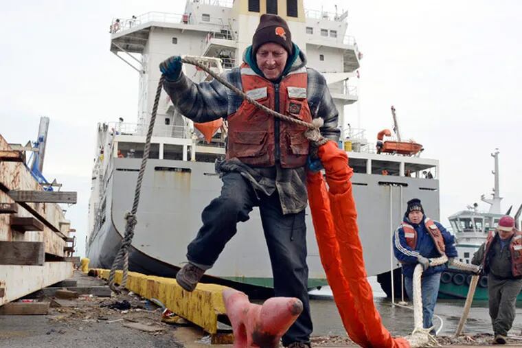 Dockworkers (from left) Michael Coyle, Patrick Coyle, and Alfie Rudzinski place a mooring line on a bollard.