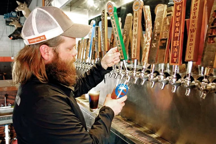 Daniel Harrison pulls a pint behind the bar at Country Boy Brewing’s taproom in Lexington, Ky. In 2012, he cofounded the craft brewer, part of an up-and-coming industry that has inspired a wave of revitalization across the city. AMY LAUGHINGHOUSE